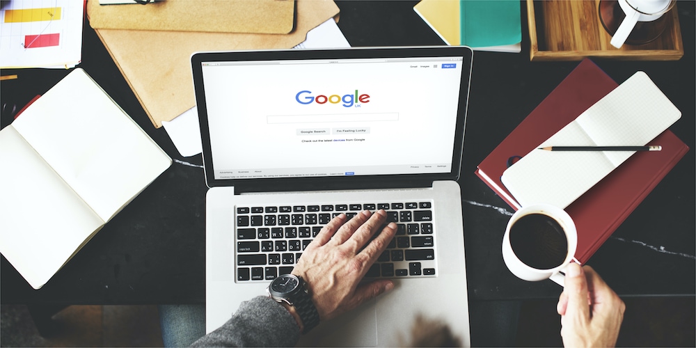 Photo from above of a person using a laptop on the Google website